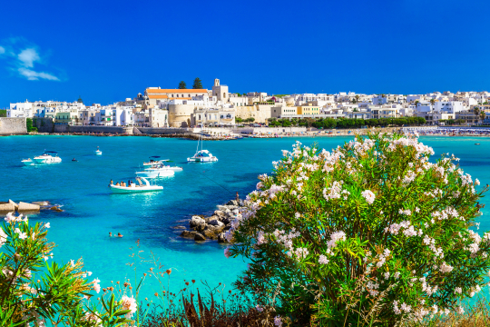 Blick über das Meer auf die Altstadt von Otranto mit kleinen Booten auf dem Meer